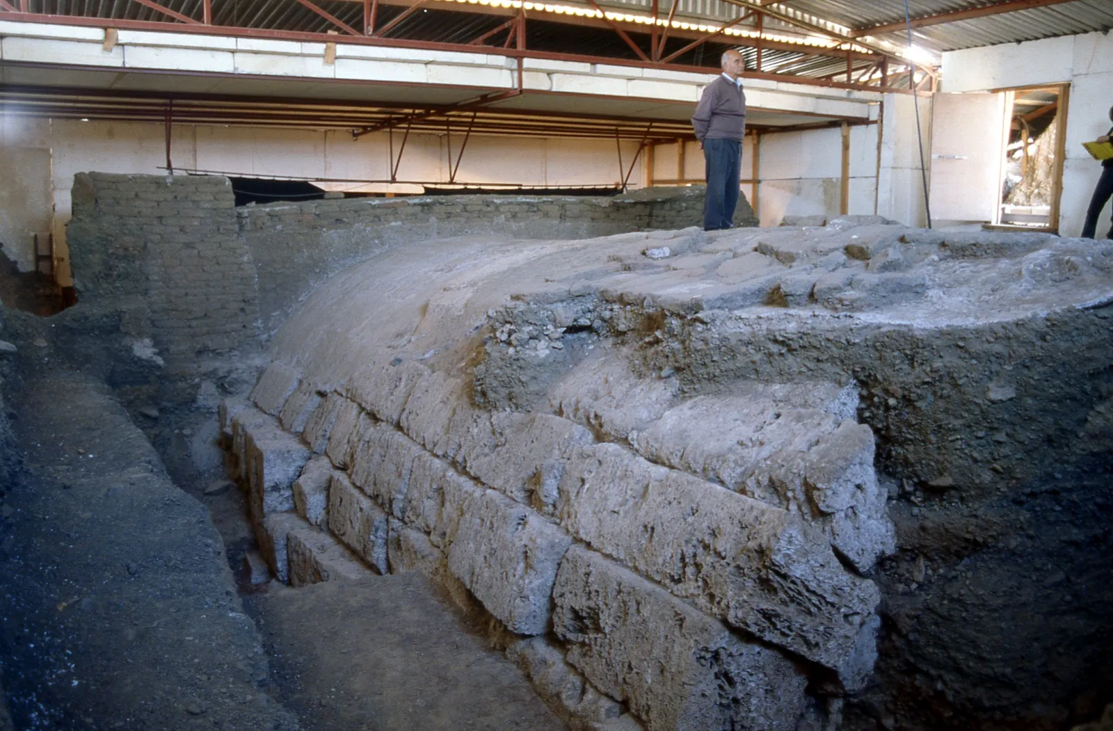 Excavated stone masonry of a royal tomb beneath the Great Tumulus at Vergina, under a protective shelter.